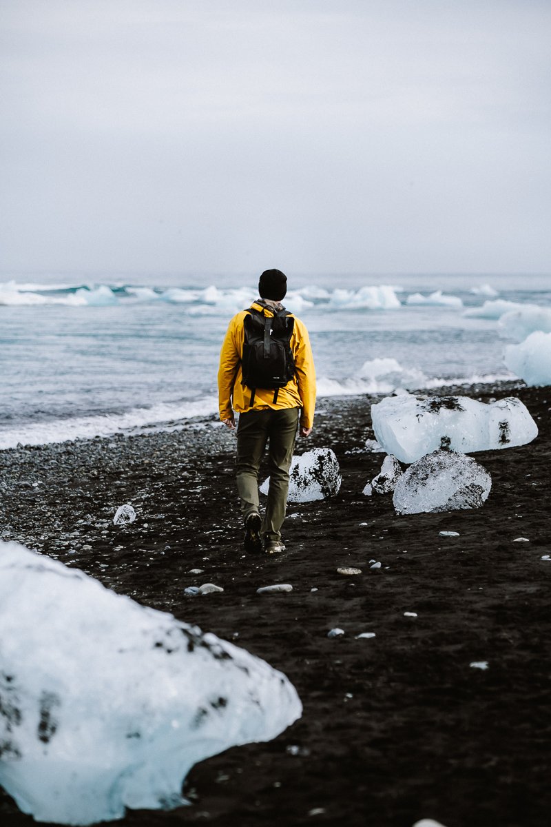 Guy walking through the icebergs on Diamond Beach Iceland