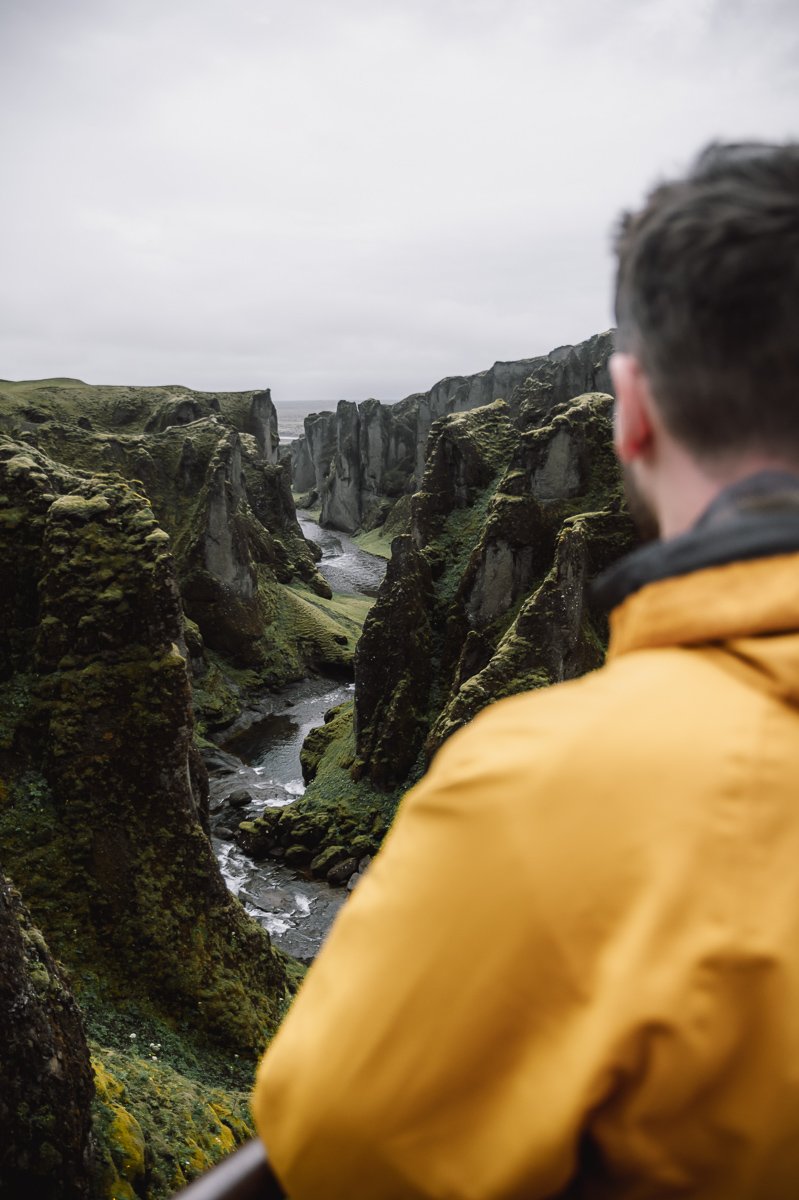 A guy looking down the Fjaðrárgljúfur Canyon during an Iceland holiday