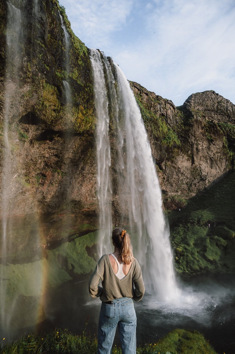 A girl standing at the waterfall Seljalandsfoss in Iceland