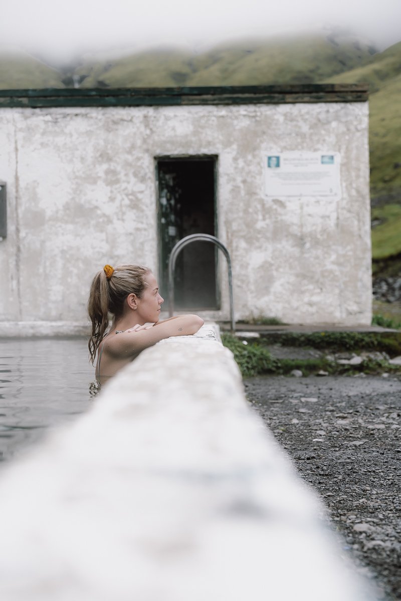 Relaxing on the edge of the Seljavallalaug Swimming Pool which is a hot spring on Icelands Ring Road Itinerary